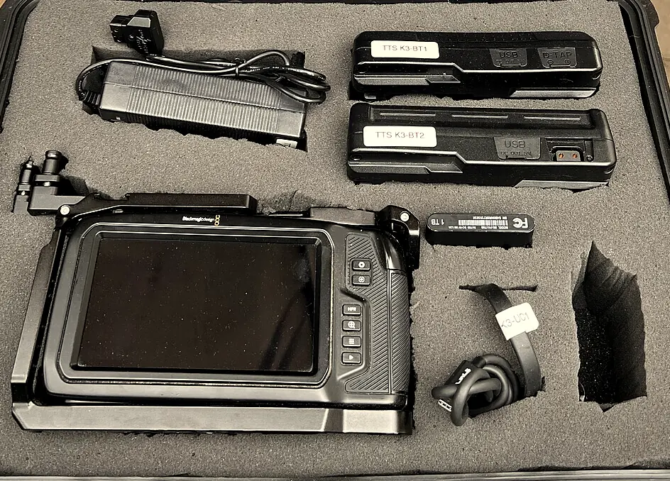 An open Tinseltown kit case: Blackmagic 6K in its cage, two V-mount batteries, charger, 1TB SSD and cable in cut foam