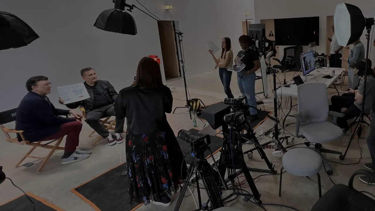 Wide view of a three-person podcast set with multiple cameras and softbox lights